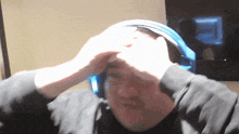 a man wearing headphones holds his head in pain