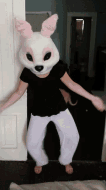 a person wearing a bunny mask and white pants is standing in a doorway