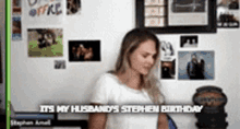 a woman in a white shirt is standing in front of a wall that says it 's my husband 's stephen birthday