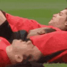 a man in a red shirt is laying on his back with the words football transfers on the bottom