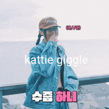 a woman wearing a hat and a denim jacket says katie giggle in a foreign language