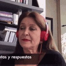 a woman wearing red headphones is sitting in front of a bookshelf .