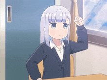 a girl with white hair and blue eyes is sitting at a desk with her fist up