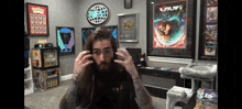 a man with a beard is wearing headphones in a room with posters on the wall and a sign that says pokemon