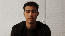 a man in a black shirt is making a funny face while looking at the camera .