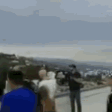 a blurry picture of a group of people standing on a hill overlooking a body of water