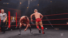 two men are wrestling in a ring with a uk logo on the wall