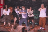 a group of people are dancing on a stage in front of a sign that says ips
