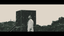 a man in a white shirt is standing in front of a black box in the rain