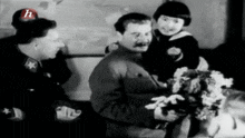 a black and white photo of a man holding a little girl with the letter h on his hat