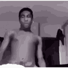 a man without a shirt is standing in a room .