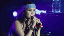 a woman singing into a microphone wearing a headband with the letter g on it