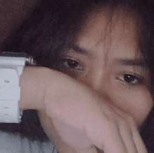 a woman covering her face with her hand and a watch on her wrist