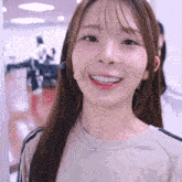 a woman wearing a microphone and a necklace smiles at the camera