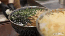a bowl of soup with seaweed and green onions on a table