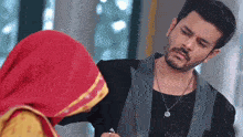a man in a suit is standing next to a woman in a red veil .