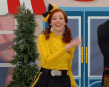 a woman in a yellow shirt and black skirt is dancing in front of a building .