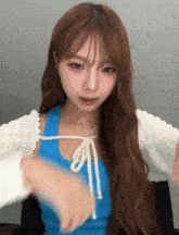 a girl with long hair is wearing a blue tank top and a white cardigan