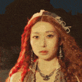 a woman with red hair is wearing a necklace and earrings