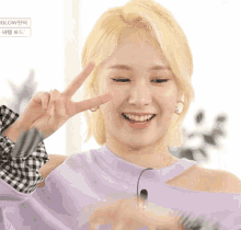a woman in a purple sweater is giving the peace sign