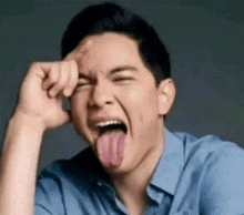 a man in a blue shirt is sticking his tongue out while making a funny face .