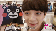 a young boy is smiling in front of a kumamon bear
