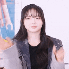 a young woman with long hair and bangs is wearing a black shirt and a leather jacket .