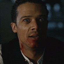 a man with blood on his face is smiling with his mouth open