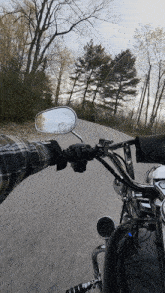 a man is riding a motorcycle down a road with trees in the background