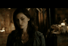 a woman with long dark hair is looking at the camera