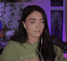a woman wearing headphones and a nose ring is sitting in front of a microphone in a room .
