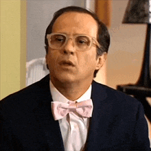 a man wearing glasses and a pink bow tie is making a funny face