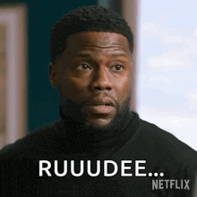 a man wearing a black turtleneck is making a funny face and saying ruudee .