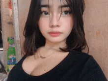 a woman in a black shirt with a necklace on her neck looks at the camera