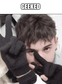 a man wearing black gloves is making a peace sign .