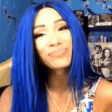 a woman with blue hair and a necklace is smiling .