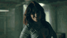 a woman is standing in a dark room wearing a green dress .