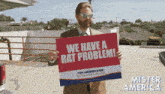 a man holding a sign that says " we have a rat problem "