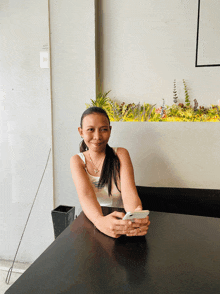 a woman sits at a table with a phone in her hand