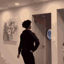 a man standing in front of a door with a clock on the wall that says ee
