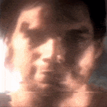 a close up of a man 's face with a glowing light behind him .