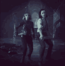 a man and a woman are standing next to each other in a dark room holding swords