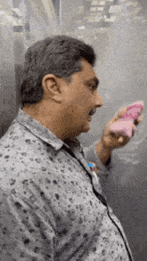 a man is standing in an elevator holding a pink object .