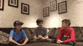 three boys are sitting on a couch and one of them is wearing a hat that says alto
