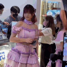 a woman in a pink and purple dress stands in a crowd