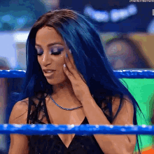 a woman with blue hair is standing in a wrestling ring with the hashtag #thenextbigthing