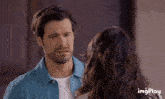 a man in a blue shirt is looking at a woman in a white shirt with imgplay written below him