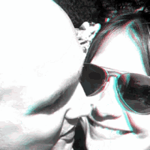 a woman wearing sunglasses is kissing a man 's forehead