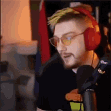 a man with a beard wearing headphones and sunglasses is talking into a microphone .
