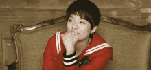 a young boy in a red jacket is sitting on a couch